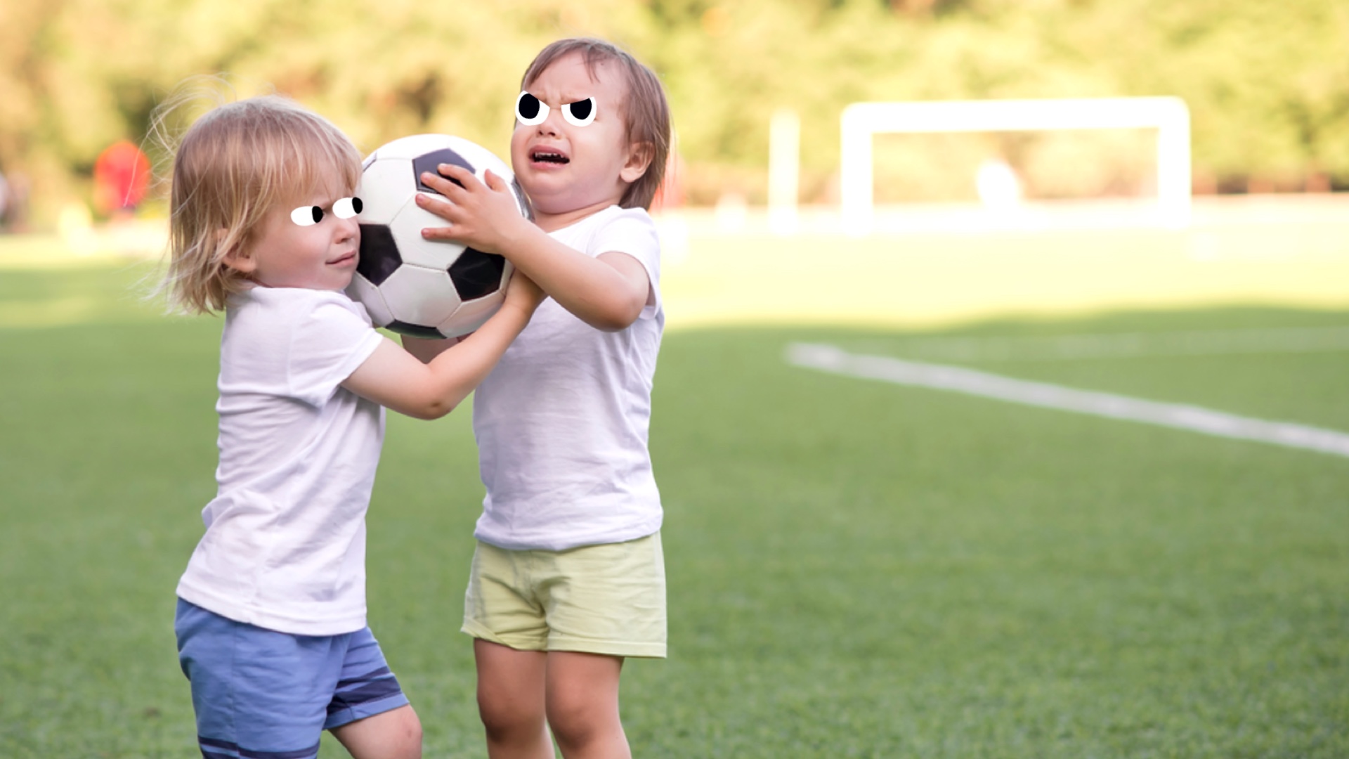 Two young children having a disagreement over a football 