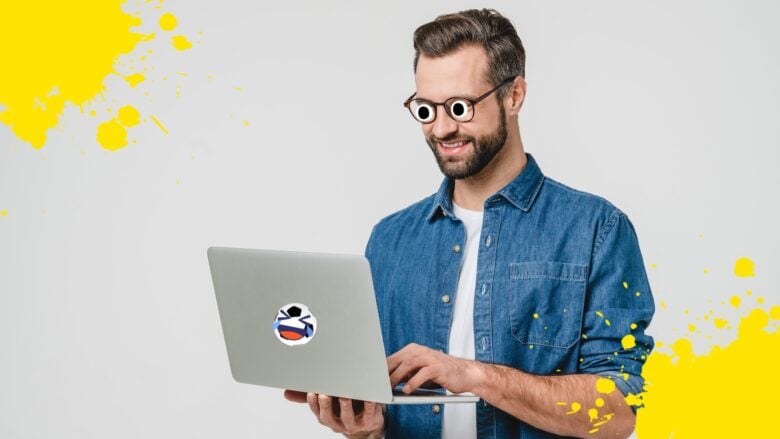 A man on a silver laptop decorated with a football sticker