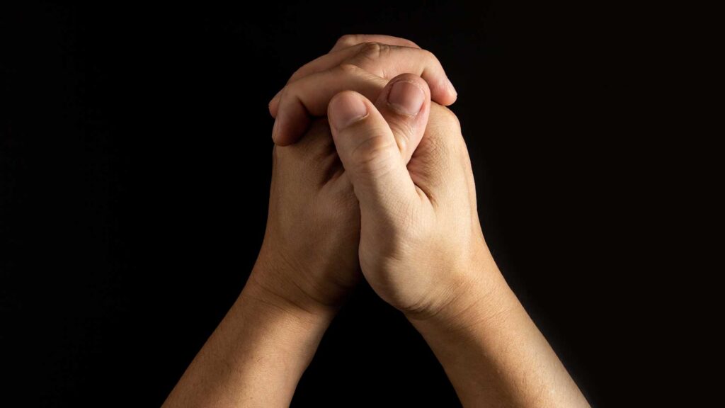 Praying hands against a dark background 